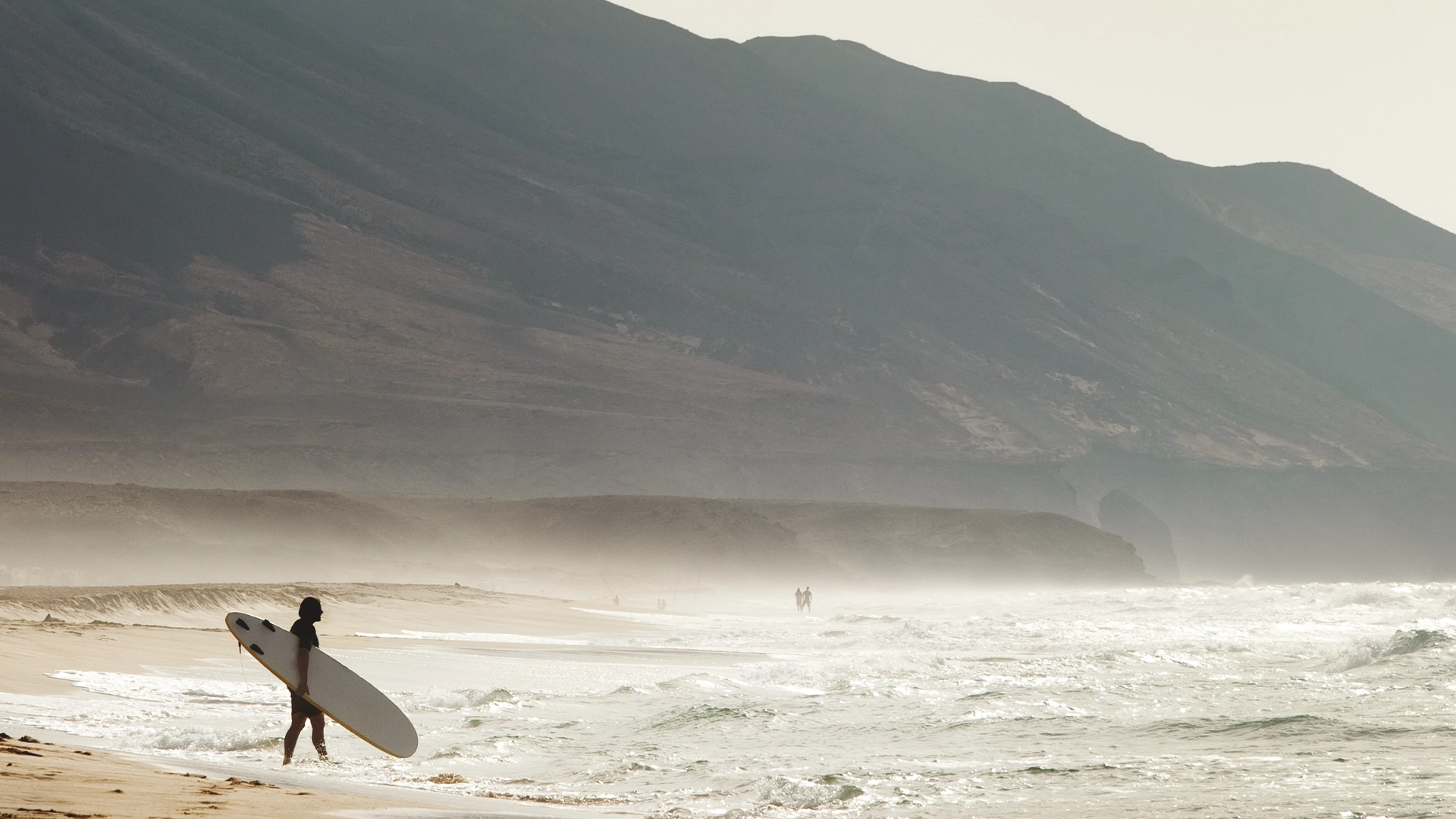 Un joven se dirige a surfear en una de las playas de Fuerteventura.